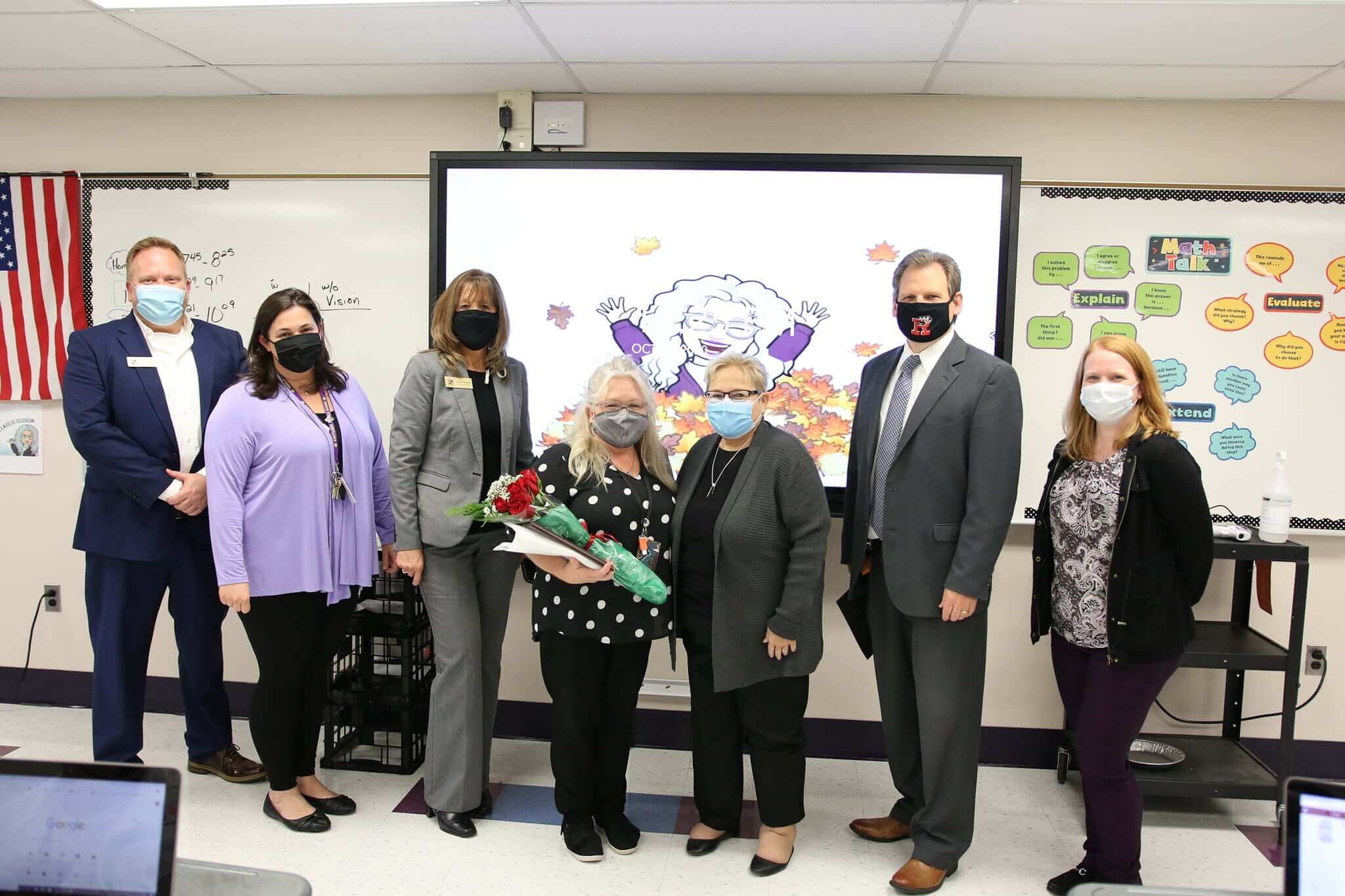 Educators standing by a interactive flat panel