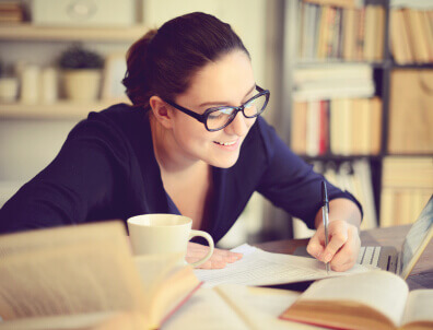 Woman writing notes next to her laptop.