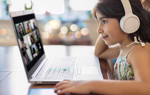 young female student using a laptop and headphones at home for virtual learning.