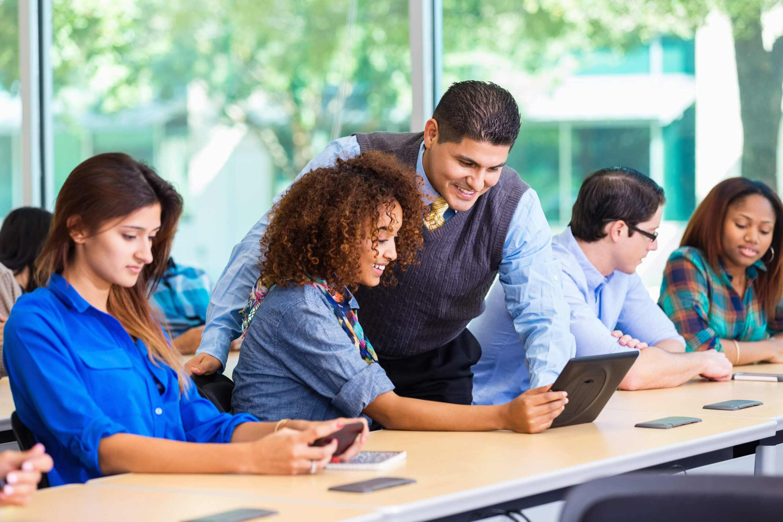 Professor assisting student using digital tablet in class