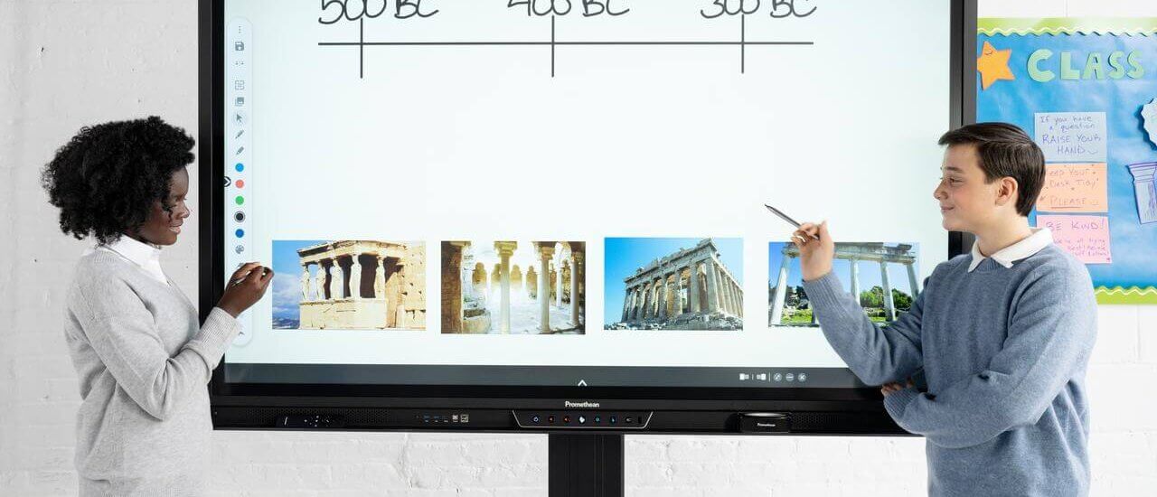 Two students using an interactive display/ interactive whiteboard in the classroom working on a history lesson