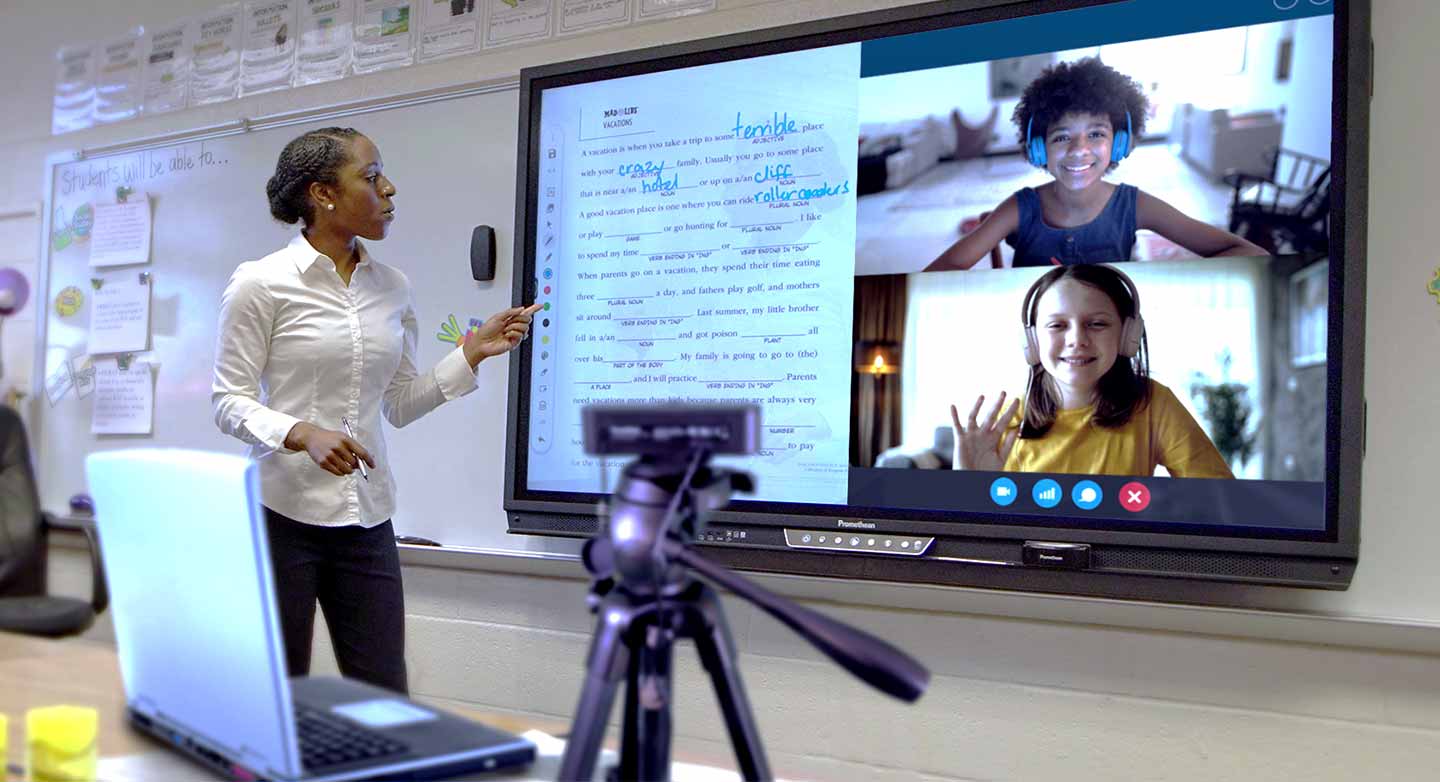  Une enseignante fait son cours en distanciel à l’aide de plusieurs équipements numériques connectés.
