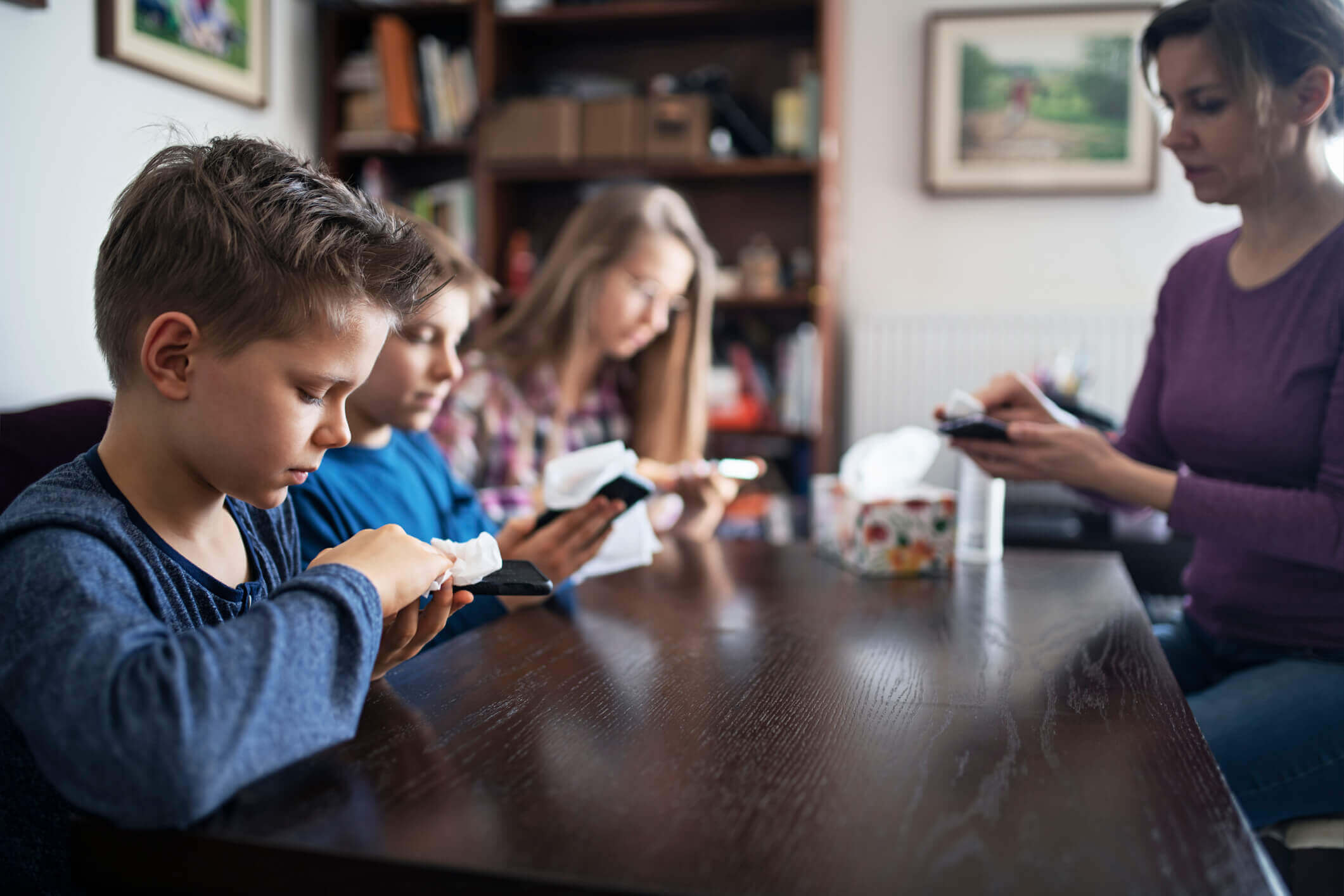 Des élèves et une adulte nettoient leurs équipements électroniques.
