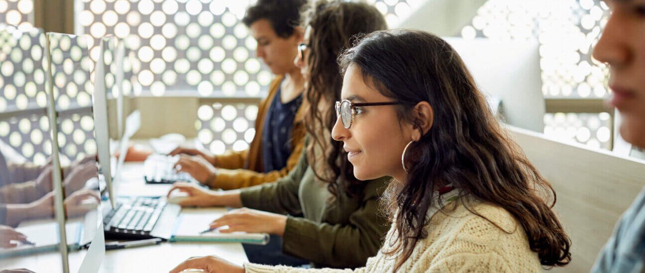 Young female student studying on a computer in a classroom.