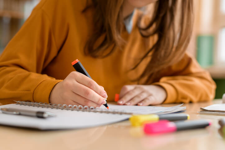 Student highlighting notes while learning in class