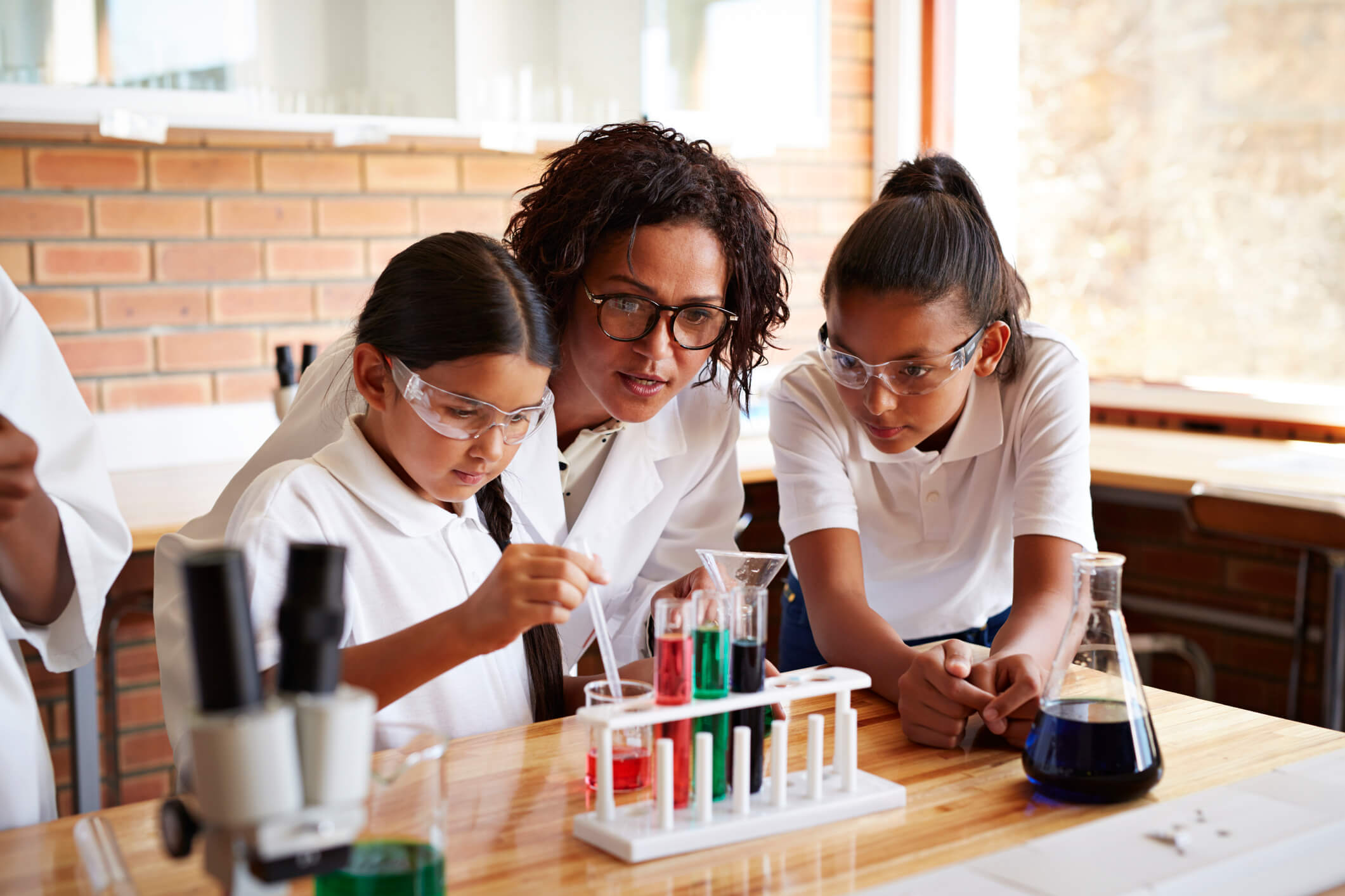 Teacher assisting students with a science project with the help of Symphony Classroom by Merlyn Mind